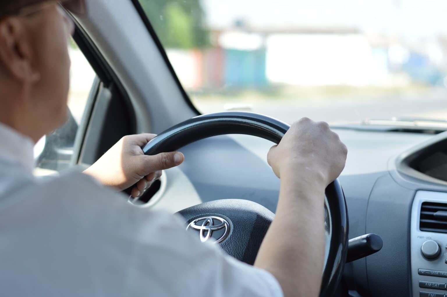 Man's hands on the steering wheel as he drives his car.