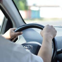 Man's hands on the steering wheel as he drives his car.