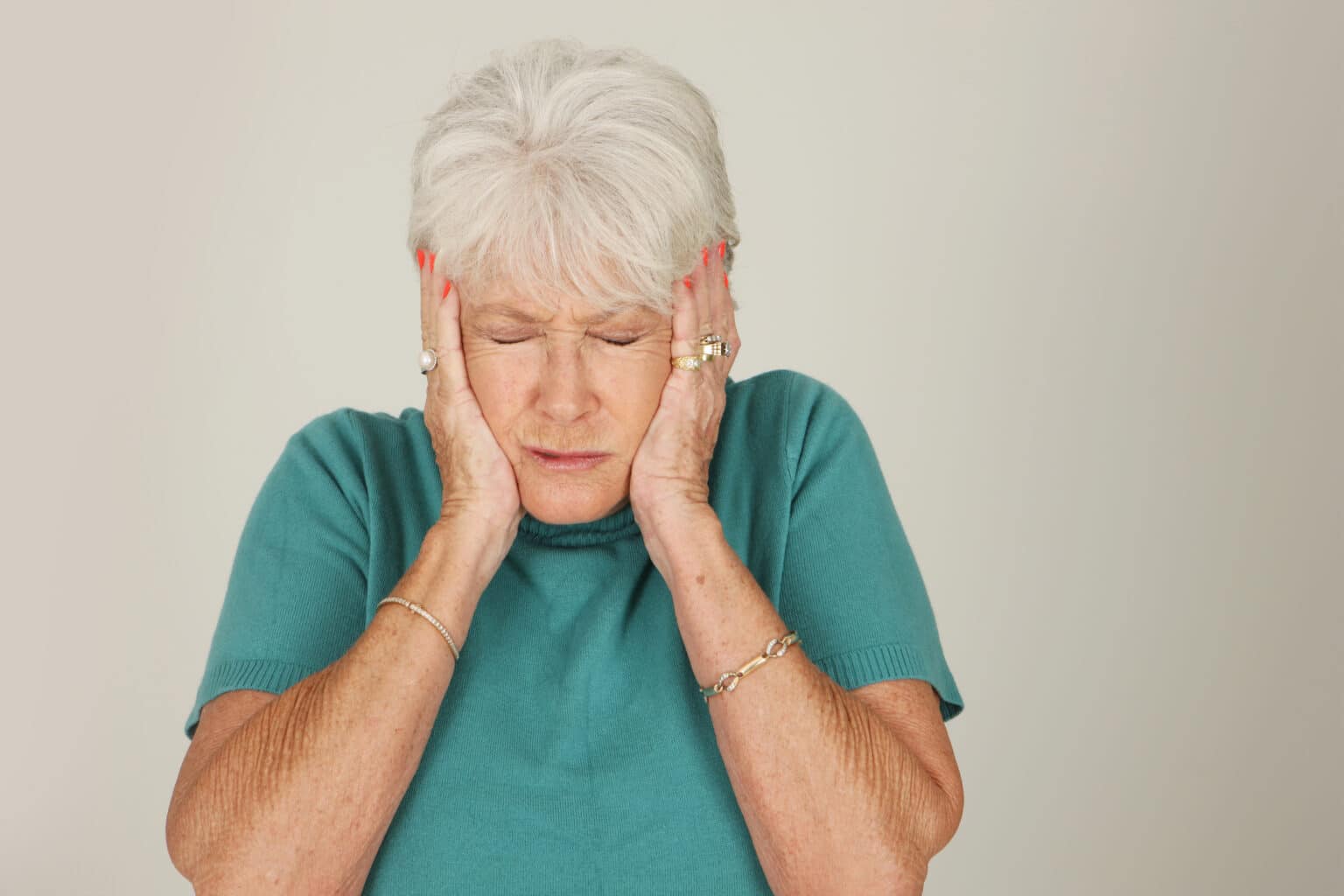 Senior woman covering her ears with her hands.