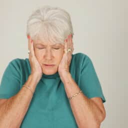 Senior woman covering her ears with her hands.