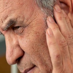 close up image of a man touching his ear