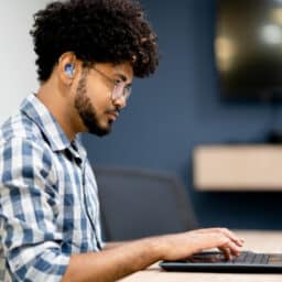 Side view of hearing impaired man working on laptop at office