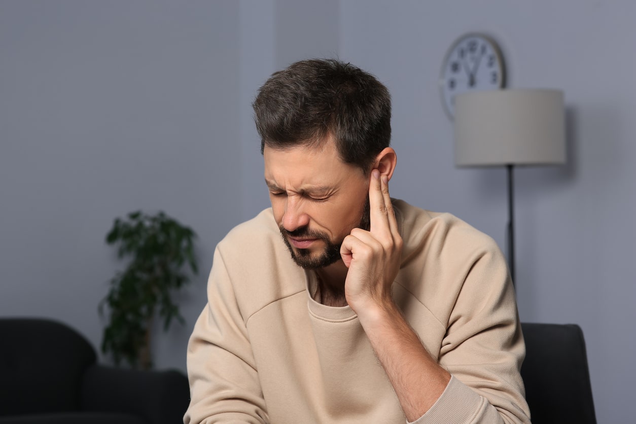 Man holding his ear experiencing tinnitus.