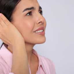 Woman with tinnitus putting a hand over her ear