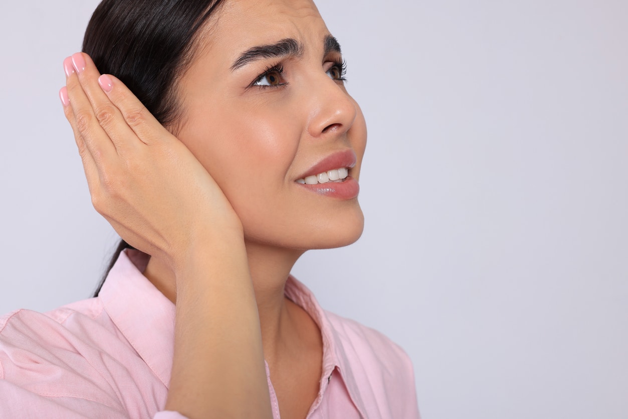 Woman with tinnitus putting a hand over her ear.
