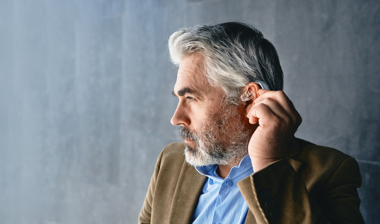 Man places hearing aid over ear