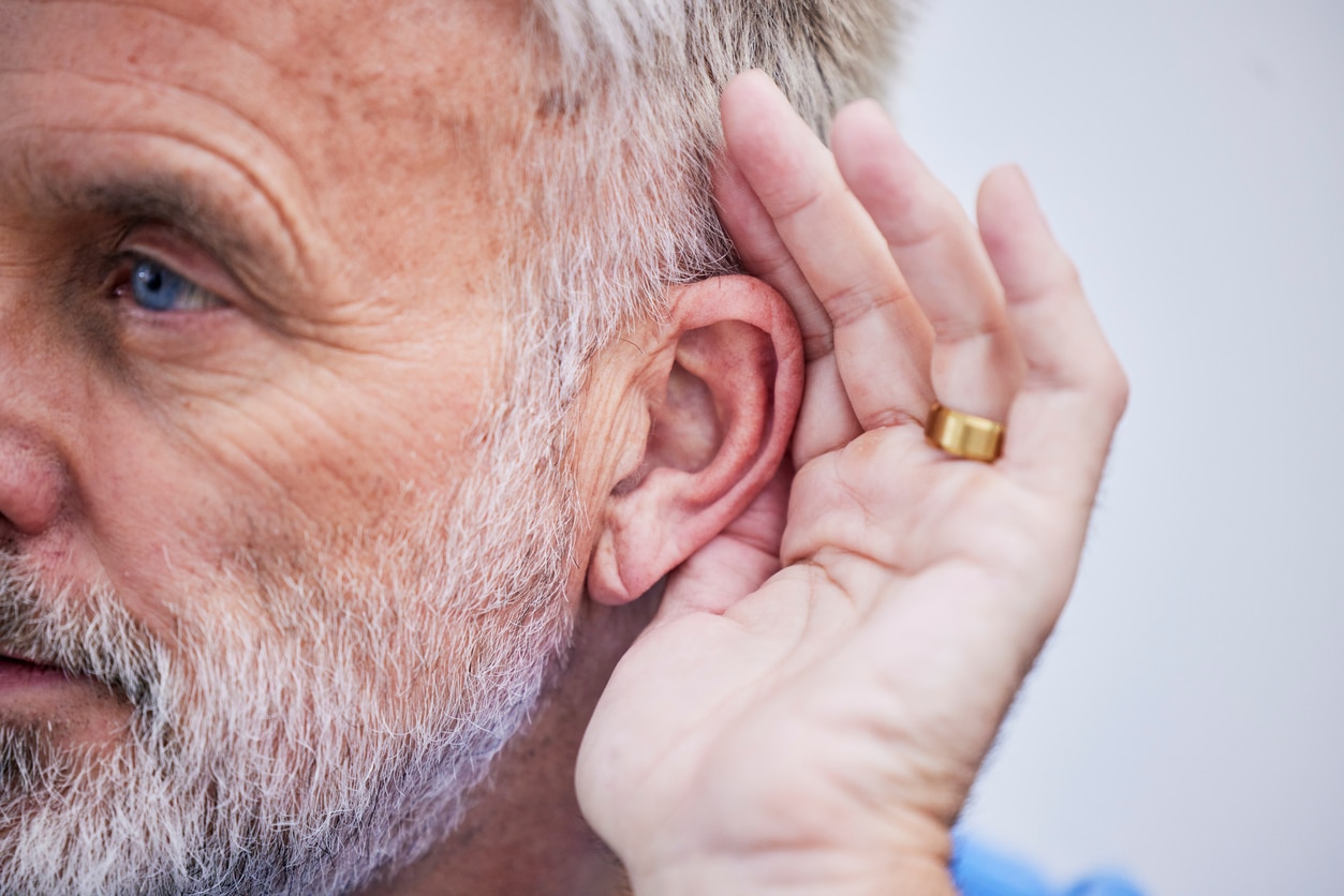 Man with hearing loss gestures behind ear