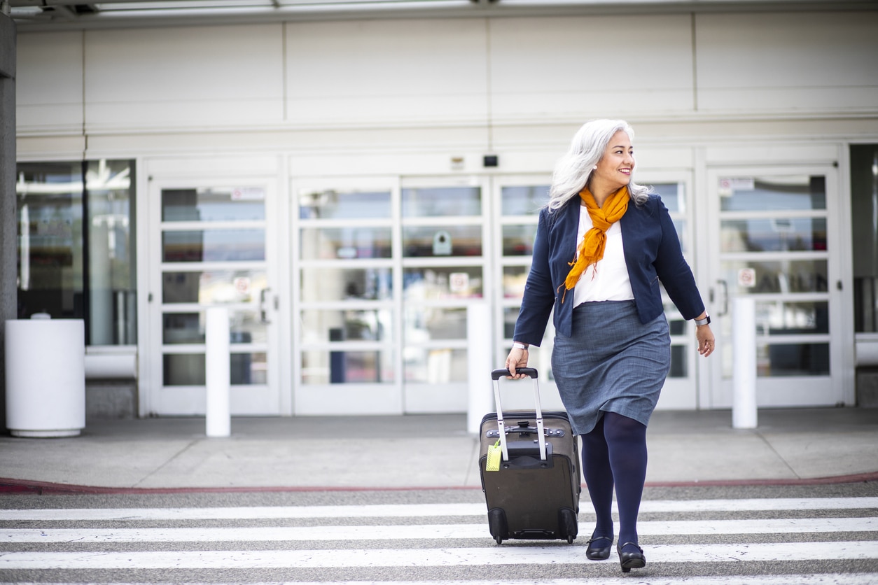 Senior woman carrying a suitcase at the airport.