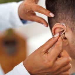 Audiologist putting a hearing aid on a patient