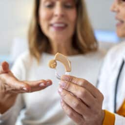 Audiologist showing a hearing aid to a patient