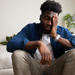 Tired man sitting on the couch rubbing his forehead.jpg