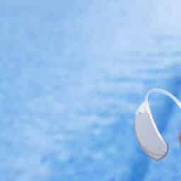 Man holding a hearing aid above a pool